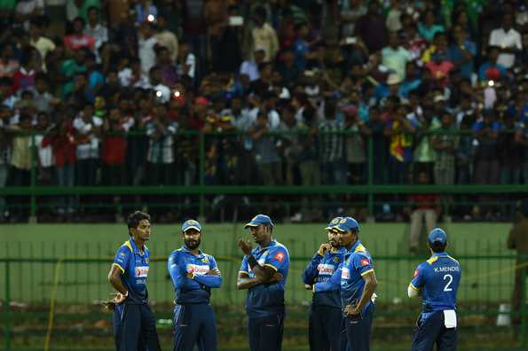 Players gather in the middle of the ground after the crowd trouble in Pallekele Players gather in the middle of the ground after the crowd trouble in Pallekele